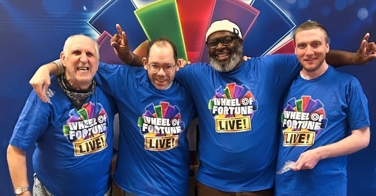 A TLC Direct Support Professional poses for a picture with three smiling individuals at a Wheel of Fortune Live event.