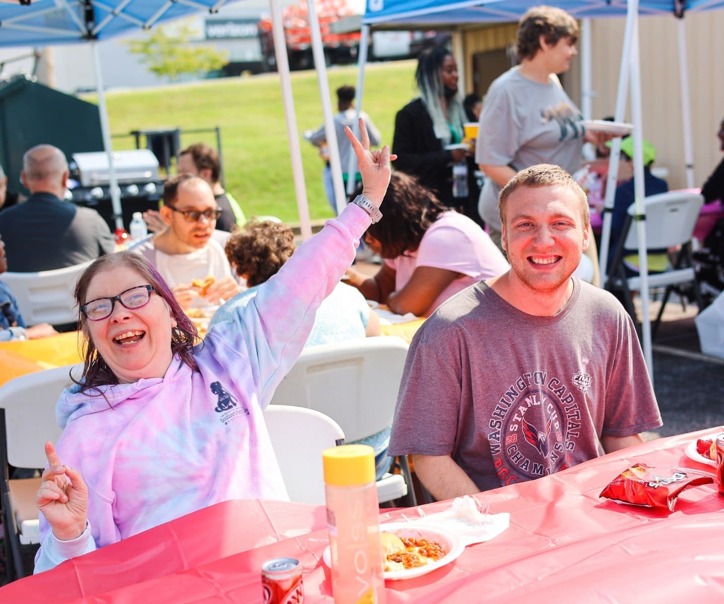 Two TLC individuals smile for a photo an at outdoor picnic.