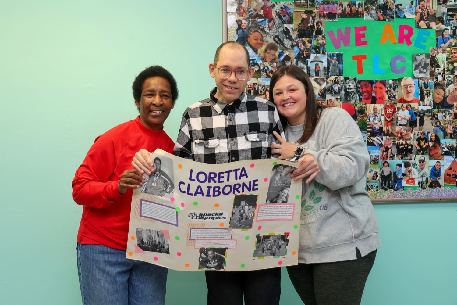 Members of the TLC York Day Program hold a poster and pose for a picture with Loretta Claiborne, renowned Special Olympian and advocate for people with disabilities.