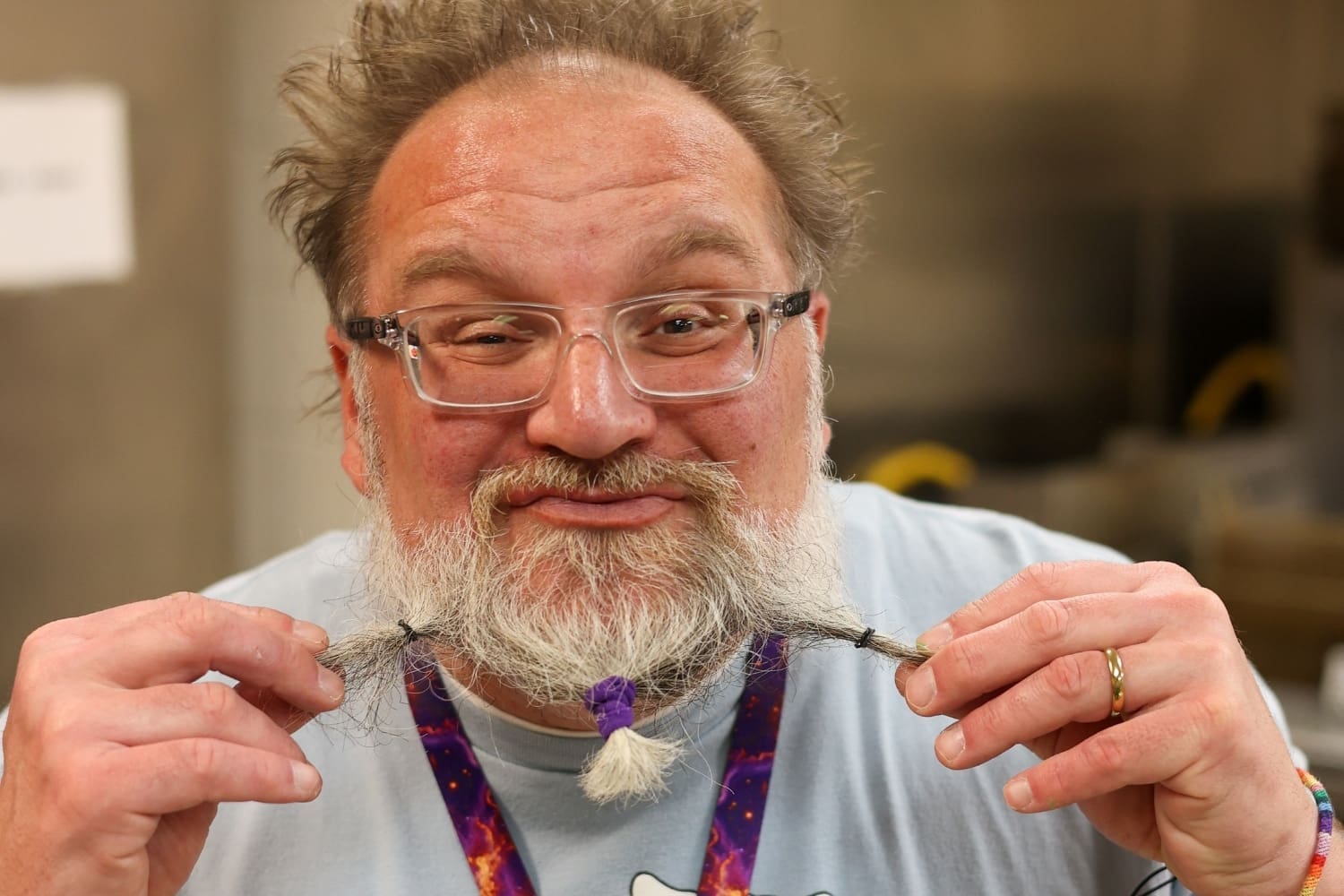 A TLC staff member with a braided beard smiles at the camera inside a TLC program space.